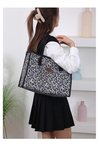Side view of large leopard print tote bag carried by model in a minimalist home setting