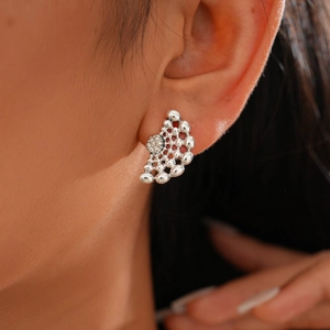 Détail de la boucle d'oreille argentée ajourée sertie de diamants sur un mannequin