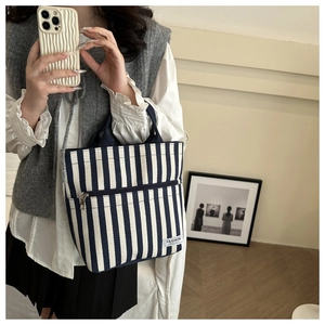Vertical blue and white striped canvas tote bag with front pocket and fashion label