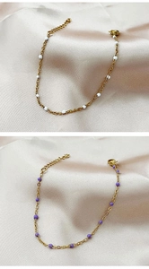 Detail of bohemian gold-plated chain bracelet with white and purple beads on satin cloth