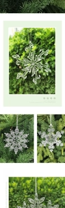 Detailed view of clear acrylic snowflake ornaments hanging on festive green pine branches