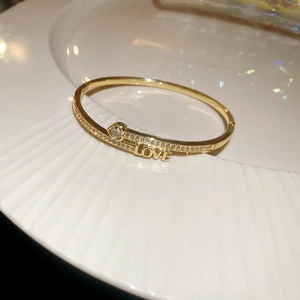 Macro shot of 18k gold plated bangle with LOVE lettering and heart-shaped zircon stones
