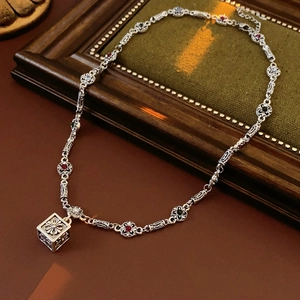 Macro shot of vintage silver flower necklace with square pendant on green fabric