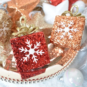 Sparkly star and gift box Christmas ornaments in red and gold glitter on a tray