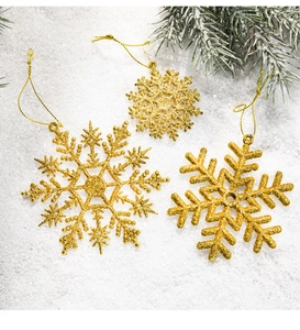 Close-up of golden glitter snowflake ornaments with strings on artificial snow background