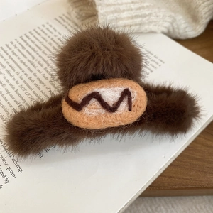 Close-up of brown flocked acrylic bread hair claw clip resting on an open vintage book