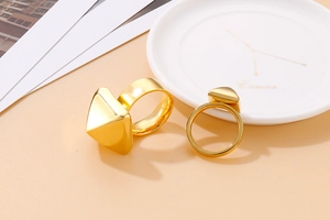 Macro shot of geometric gold triangular pyramid stainless steel ring on aesthetic props