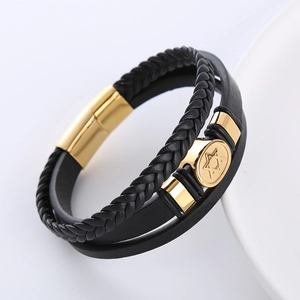 Detail eines mehrlagigen Lederarmbands in Schwarz mit goldenem Stern und Stahlverschluss