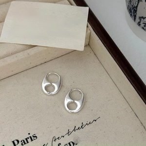 Close-up of geometric saddle silver earrings on minimalist fabric jewelry box