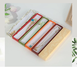 Top view of assorted jewelry boxes with pearl hairpins and gold necklaces in vibrant colors