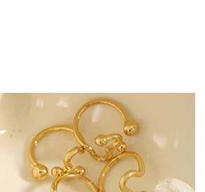 Macro detail of minimalist gold hoop earrings with sphere beads in a ceramic dish
