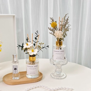 Reed diffuser set with dried flowers and essential oils in glass bottles on white