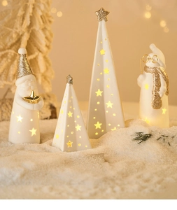 Close-up of white ceramic Christmas figurines with gold glitter and warm glowing lights