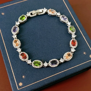 Detail of silver oval bracelet with multicolored gemstones and zircon accents on a jewelry box