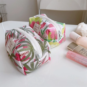 Detail view of floral jacquard pouches with white zipper and textured fabric