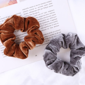 Detail of coffee and grey velvet scrunchies set with a soft texture on a white background