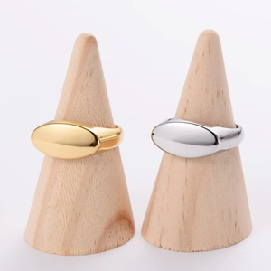 Minimalist oval flat-top stainless steel rings in gold and silver on wood stands