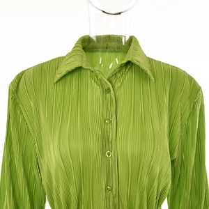 Detailed view of the wrinkled green fabric texture and button closure on this women shirt