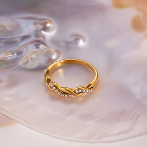 Detail of twisted gold titanium steel ring with elegant pearls on a shell base