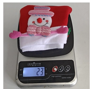Detail shot of a plush snowman Christmas hat on a digital scale weighing exactly 23 grams
