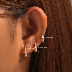 Model wearing a set of three gold earrings with zircons in 0.6cm, 0.8cm, and 1cm sizes