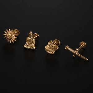 Flat back gold steel piercing studs featuring sun, Buddha, owl, and sword shapes
