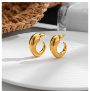 Macro detail of chunky gold plated stainless steel hoop earrings on a ceramic dish