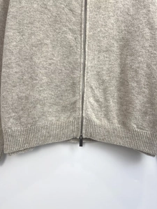 Close-up of premium grey knit sweater showing metal zipper and ribbed hem texture
