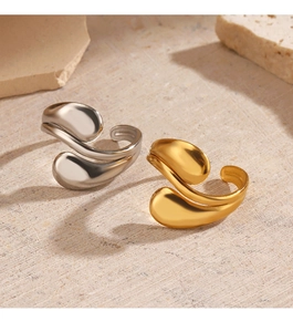 Close-up of gold and silver teardrop open rings on a textured stone background