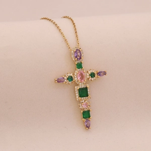 Macro shot of gold cross pendant with colorful gemstones and sparkling zircon borders