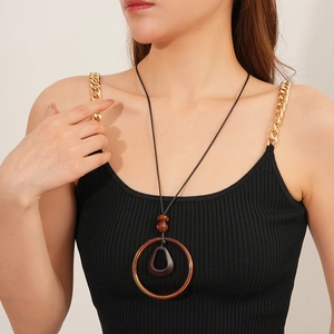 Detail of a vintage resin pendant on a black cord necklace worn by a fashion model