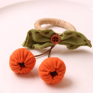 Detailed view of woven rattan hair tie with burlap bow and plush orange pumpkins
