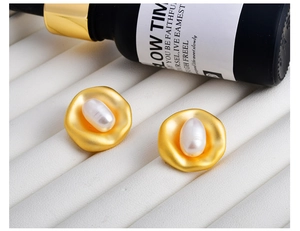 Macro detail of French vintage baroque stud earrings with gold matte metal and white pearl