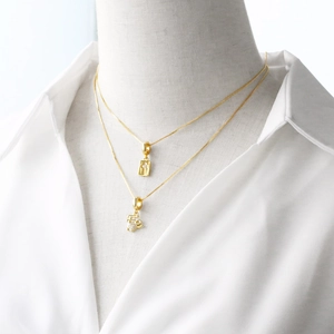 Double-layered 18k gold plated necklace with cross charm and Fé pendant on woman