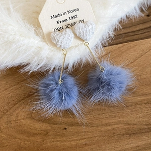 Dettaglio del ciondolo a cuore in tessuto bianco e del pompon grigio-blu dell'orecchino