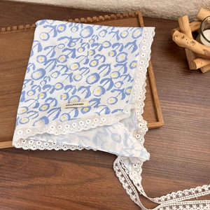 Detailed view of blue floral cotton headscarf with white lace edge and 100% cotton tag