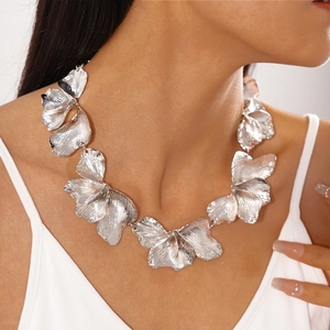 Detail shot of a silver metallic flower petal necklace on model neck with leaf textures