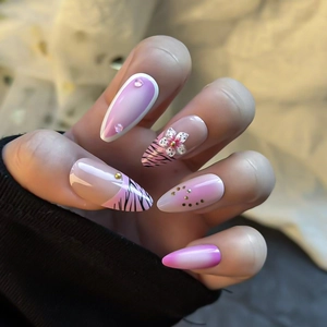 Faux ongles rose motif zèbre avec fleurs 3D et strass brillants portés à la main