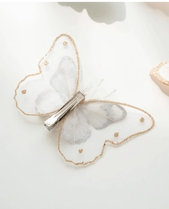 Detail showing metal alligator clip on white mesh butterfly with gold glitter edges