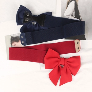 Detail of navy and red elastic waist belts with oversized bow and metal snap buttons