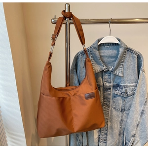 Close-up of brown canvas tote bag with adjustable strap and fashion logo patch