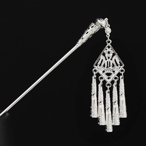 Detail of silver Miao hair stick featuring intricate cutout patterns and flowing tassels