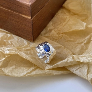 Detail of irregular textured silver ring with oval blue gemstone on vintage paper