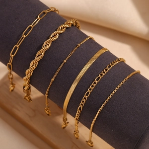 Detailed close-up of various 18K gold-plated bracelets like Figaro and rope chains on a rack