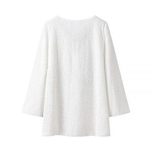 Détail de la robe blanche à manches longues montrant les paillettes et la texture fine