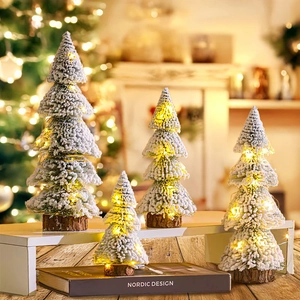 Mini snowy Christmas trees with warm LED lights and natural wooden bases on desktop