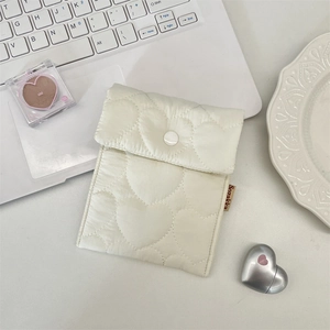 Detailed view of white quilted heart sanitary pouch with snap button and side label