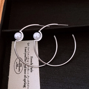 Close-up of silver-plated hoop earrings with pearl accents in a black jewelry box