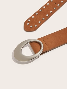 Gros plan sur une ceinture en daim marron avec boucle ovale argentée et rivets vintage