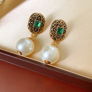 Vintage gold earrings with green square gemstone and white round pearl in a jewelry box